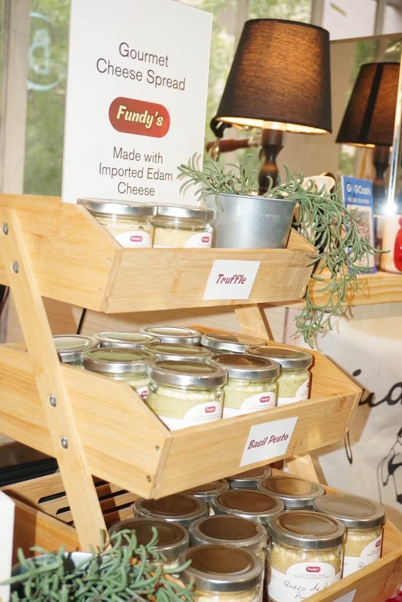 Wooden three-tier display of Fundy's Spread jars labeled Truffle, Basil Pesto and Pimiento